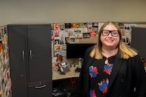 Photo of Gabrielle Dutz sitting at her desk surrounded by some of her postcards