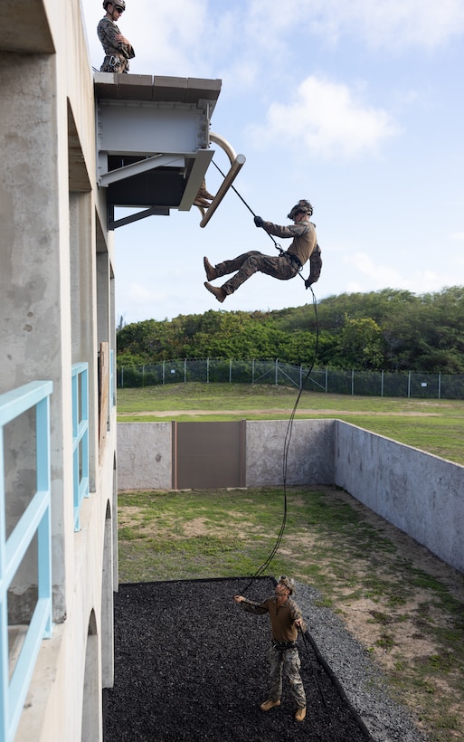 U.S. Marine Corps 1st Lt. Brett O’Connell rappels from a building with Sgt. Kai Kalamau as his belayer during a Helicopter Rope Suspension Techniques Master Course on Marine Corps Base Hawaii, Dec. 6, 2023. The course was led by HRST Master Instructors with III Expeditionary Operations Training Group, based in Okinawa, Japan, who travelled to Hawaii to certify Marines with 3d Littoral Combat Team as HRST Masters. With the certification, HRST Masters can train Marines to safely and effectively perform helicopter insertions and extractions, rappels, and other rope techniques. O’Connell, a native of Boston, is an infantry platoon commander, and Kalamau, a native of Waianae, Hawaii, is an infantry rifleman, both with 3d LCT, 3d Marine Littoral Regiment, 3d Marine Division. (U.S. Marine Corps photo by Sgt. Jacqueline C. Parsons)