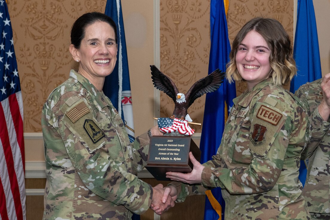 A general and Airman holding trophy