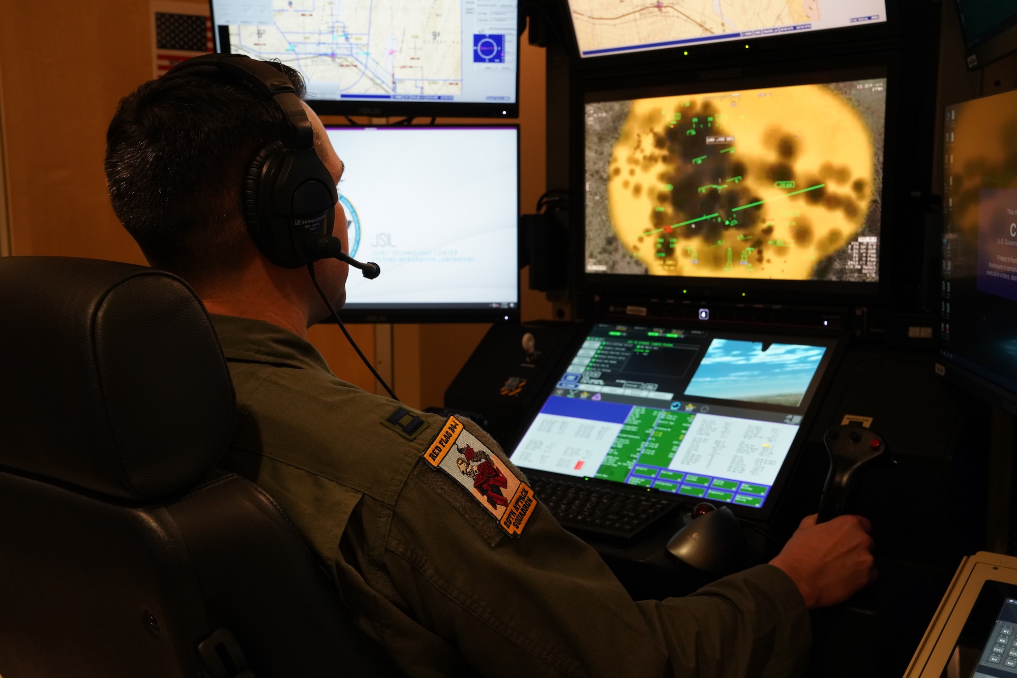 A man in a flight suit stares at a flight simulator computer screen depicting an explosion.