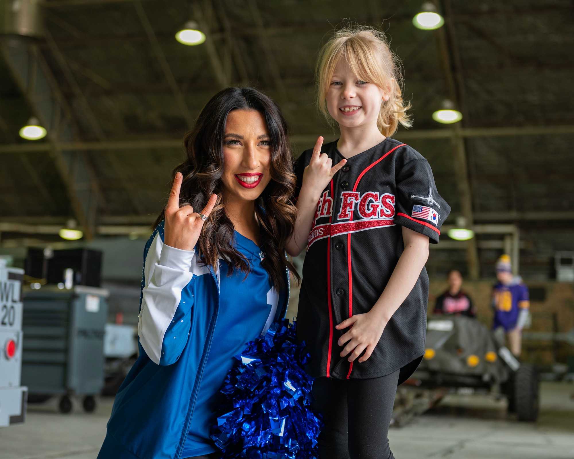 Kyleigh Creamer, an NFL cheerleader, takes a photo with a service member’s dependent from the 36th Fighter Generation Squadron, during the Pro Blitz 2024 unit visit at Osan Air Base, Republic of Korea, Feb. 10, 2024. The cheerleaders' visit was part of the NFL tour sponsored by the Armed Forces Entertainment. (U.S. Air Force photo by Staff Sgt. Aubree Owens)