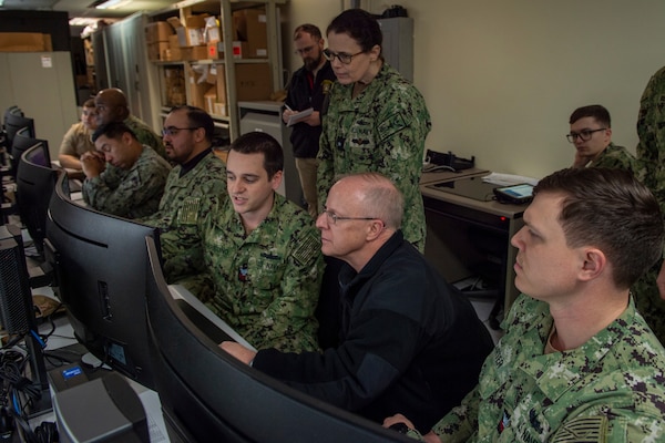 Electronics Technician Second Class Cody Carter demonstrates to Adm. Daryl Caudle, commander, U.S. Fleet Forces Command, (right) aspects of the Naval Maintenance Repair and Overhaul (NMRO) system at the Naval Information Warfare Cetner Atlantic software test laboratory at Naval Station Norfolk, Feb. 13, 2024.