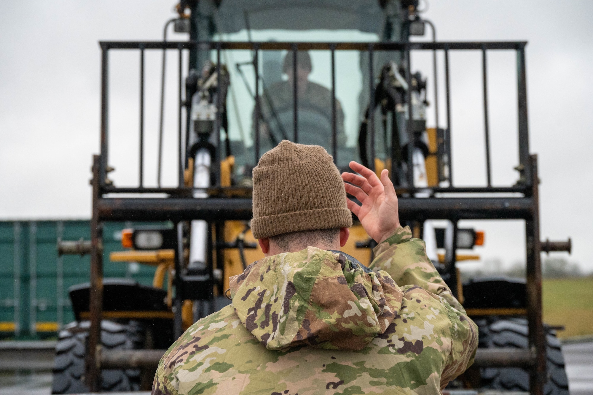 Airmen guide heavy equipment during a munitions transfer