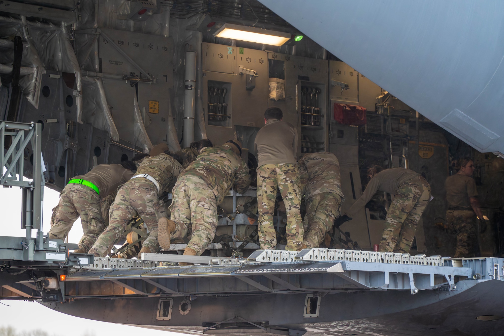 A group of Airmen push pallets aboard a C-17 Globemaster III