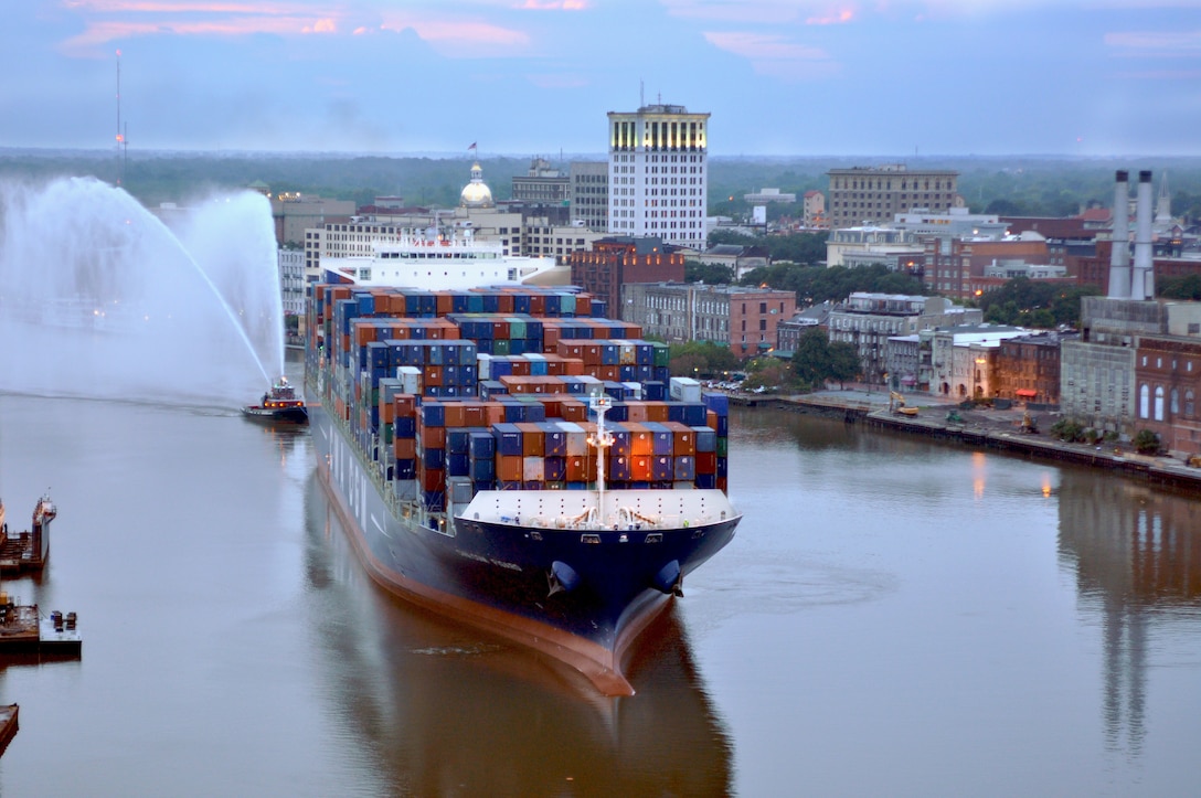 A cargo ship loaded with shipping containers during a sunrise in Savannah Harbor.