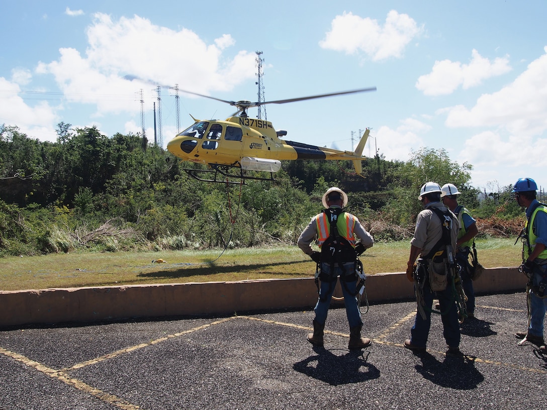 Linemen prepare to be sling-loaded from helicopters to inspect tops of high-voltage transmission towers and anchor lines