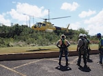 Linemen prepare to be sling-loaded from helicopters to inspect tops of high-voltage transmission towers and anchor lines