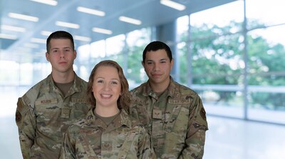 Airman 1st Class Pedro Mourin, patient travel technician, Staff Sgt. Rebecca Miranda, patient travel noncommissioned officer in charge, and Senior Airman Andres Gonzalez, patient travel technician, all assigned to the 59th Medical Support Squadron pose for a photo December 19, 2023, at Wilford Hall Ambulatory Surgical Center, Joint Base San Antonio-Lackland, Texas.