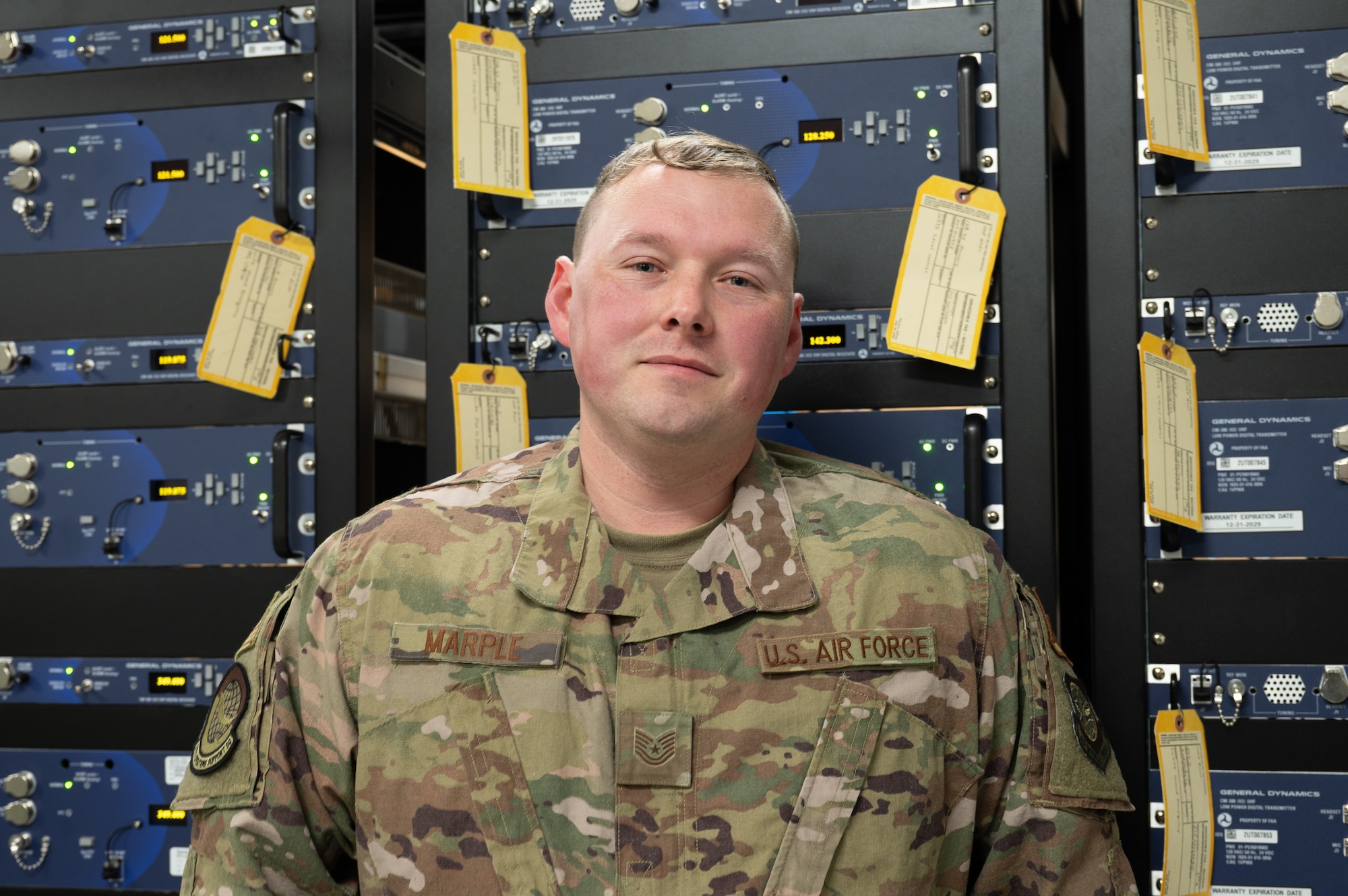 TSgt. Marple stands in front of a wall of radios