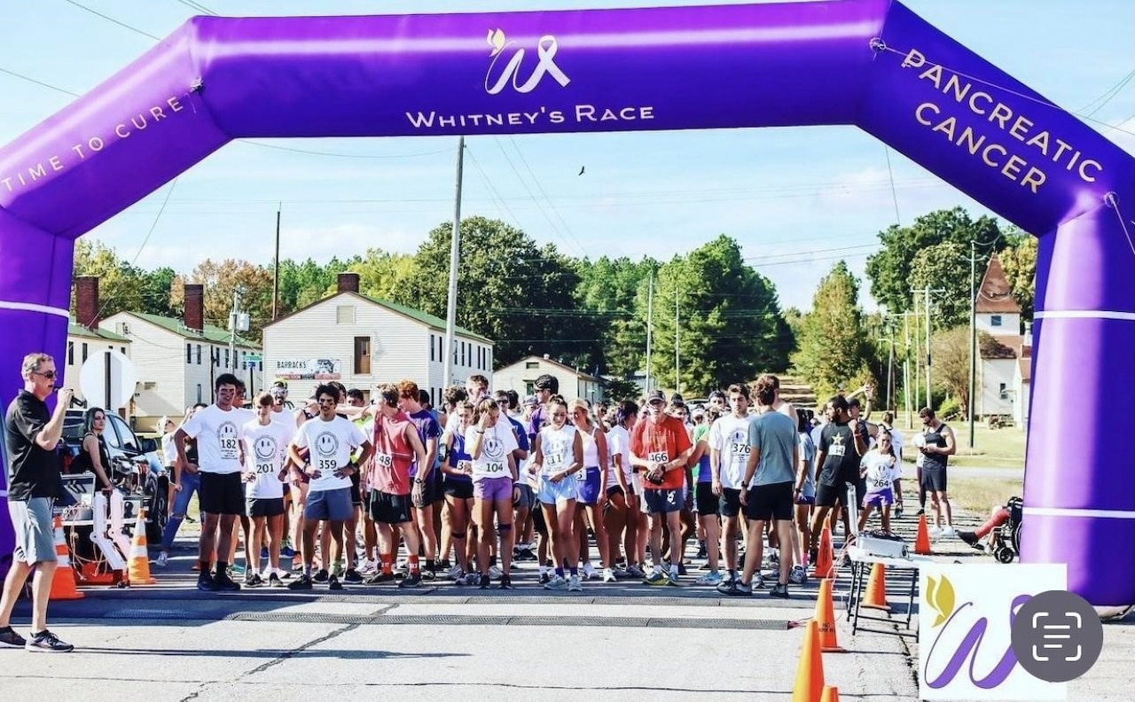 Dozens of people line up at a starting line for a foot race.