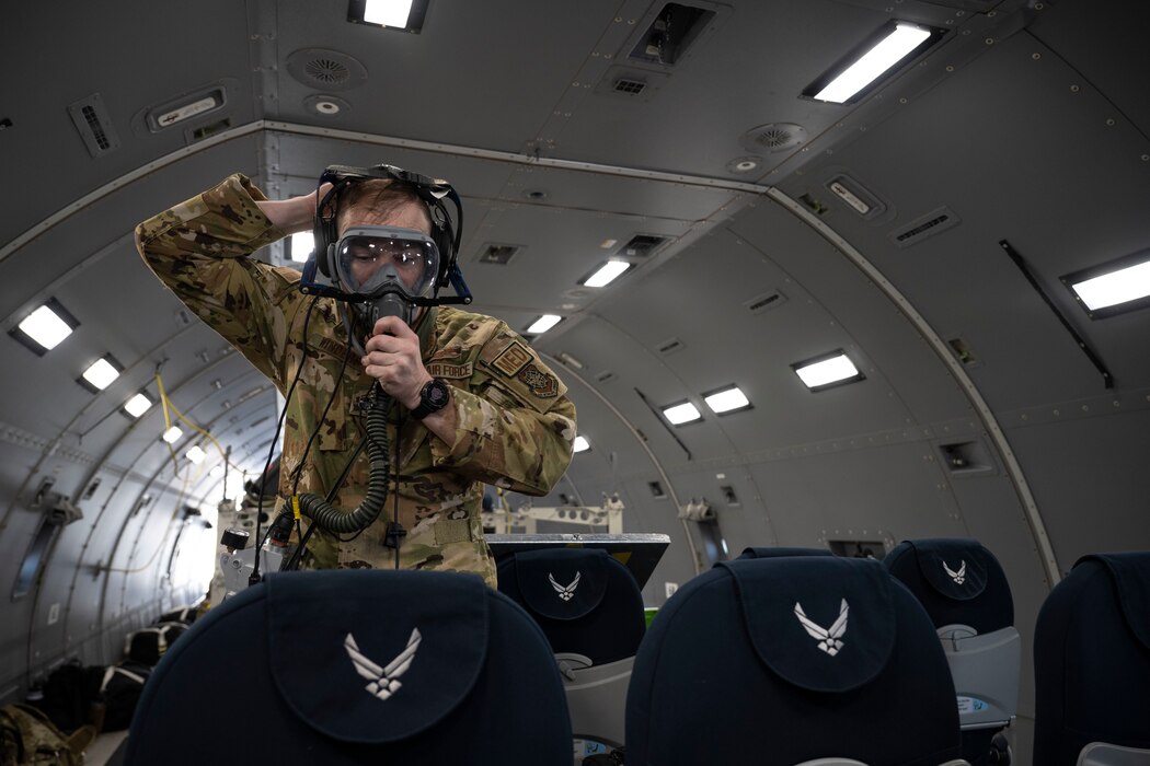 Airman puts on an oxygen mask inside an aircraft.