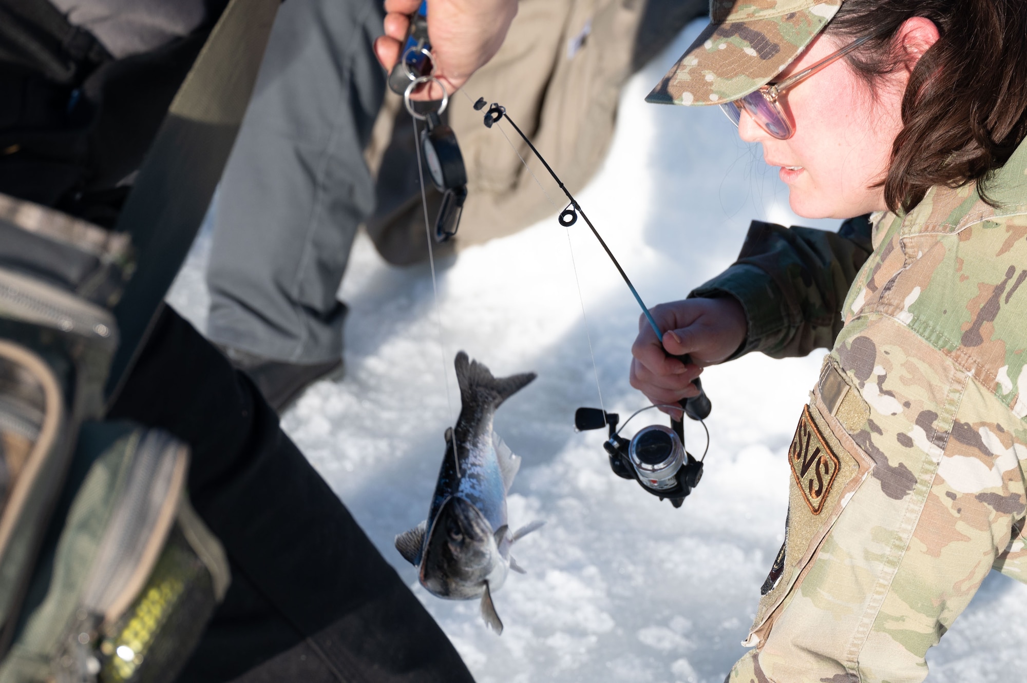 U.S. Air Force Tech. Sgt. Kathy Hernandez, 354th Force Support Squadron food section chief, catches a fish at Eielson Air Force Base, Alaska, Feb. 14, 2024.