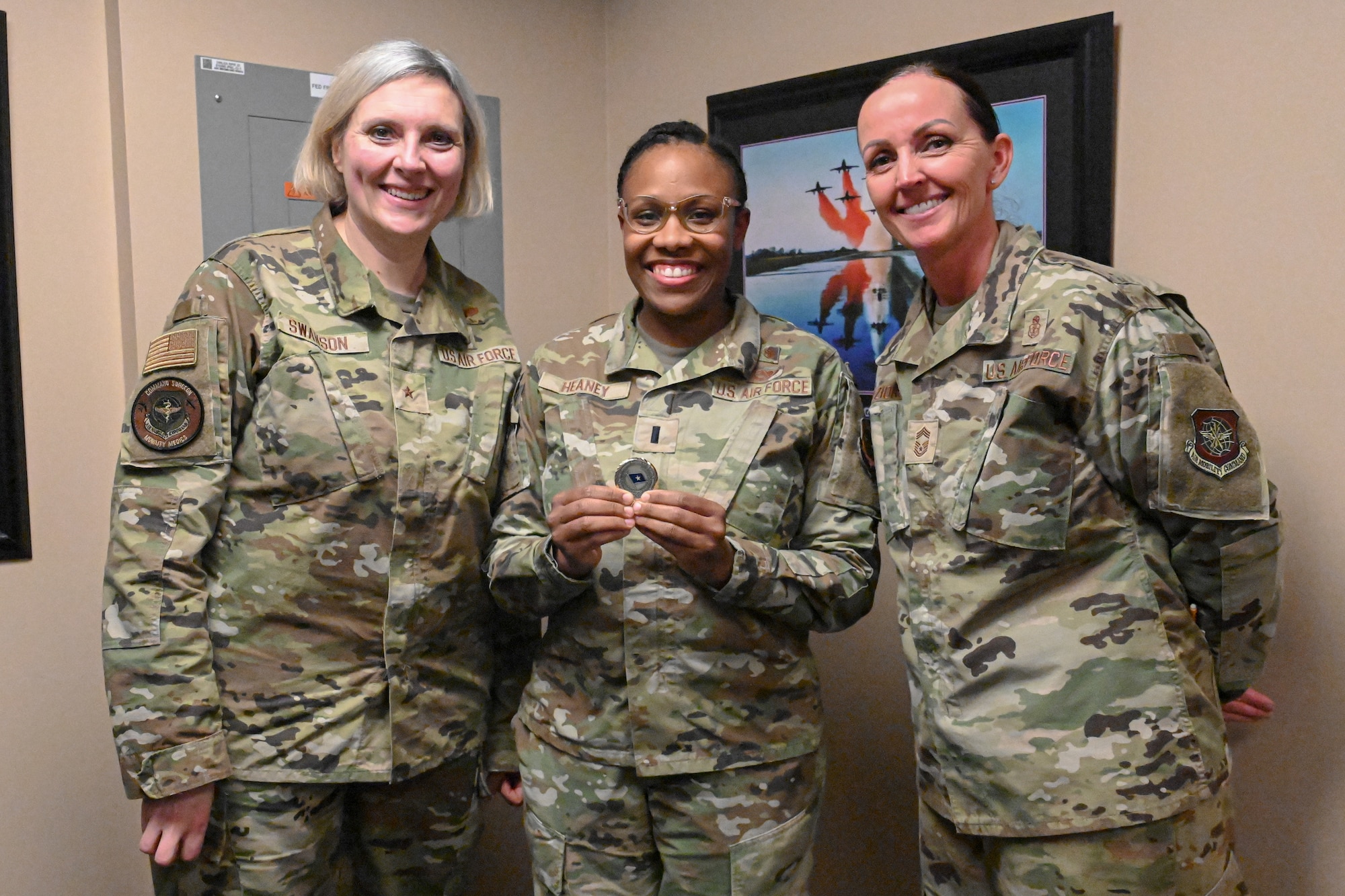 Three Airmen stand and pose for a photo as one Airman receives a coin.