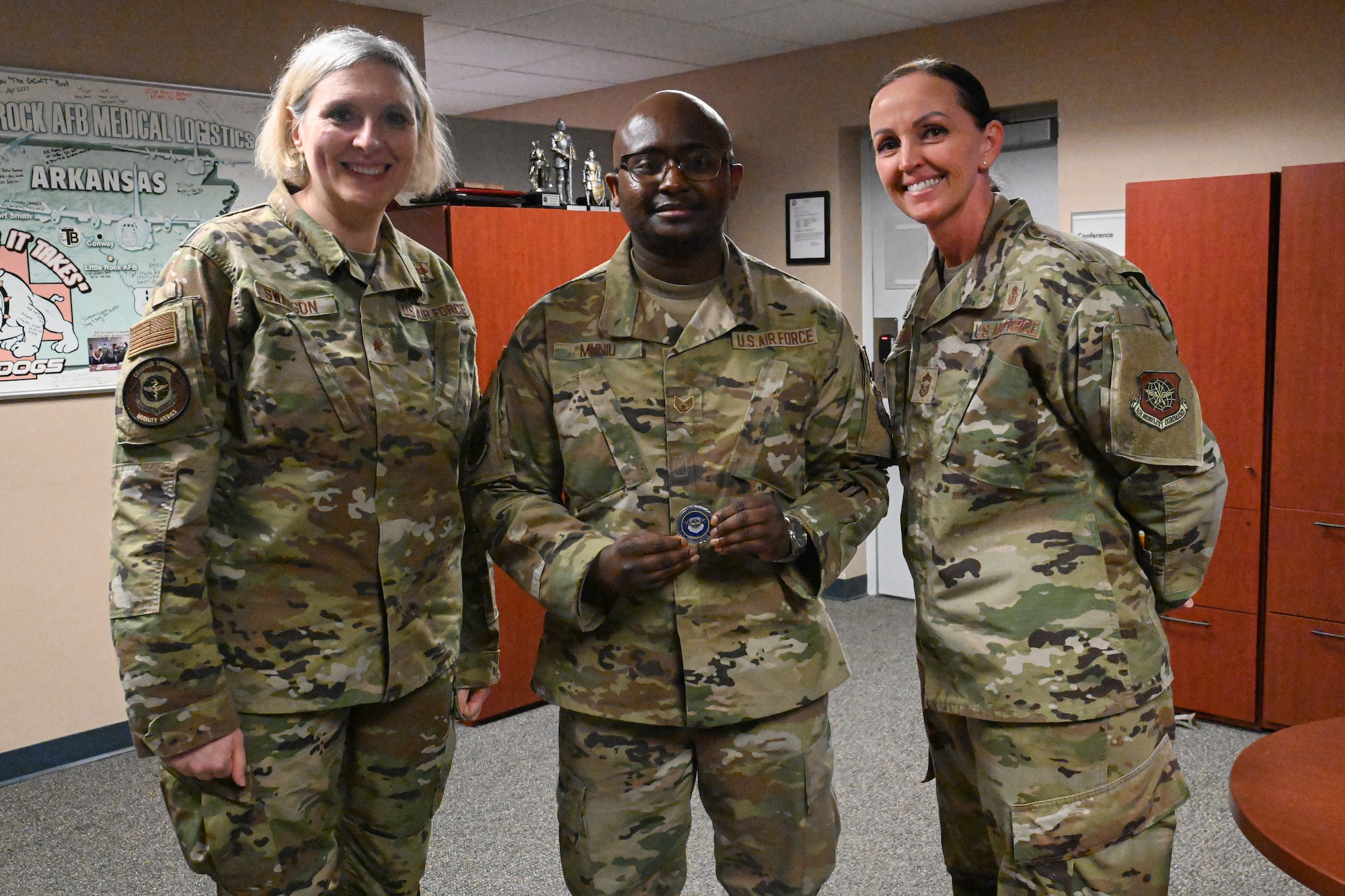 Three Airmen stand and pose for a photo as one Airman receives an award.