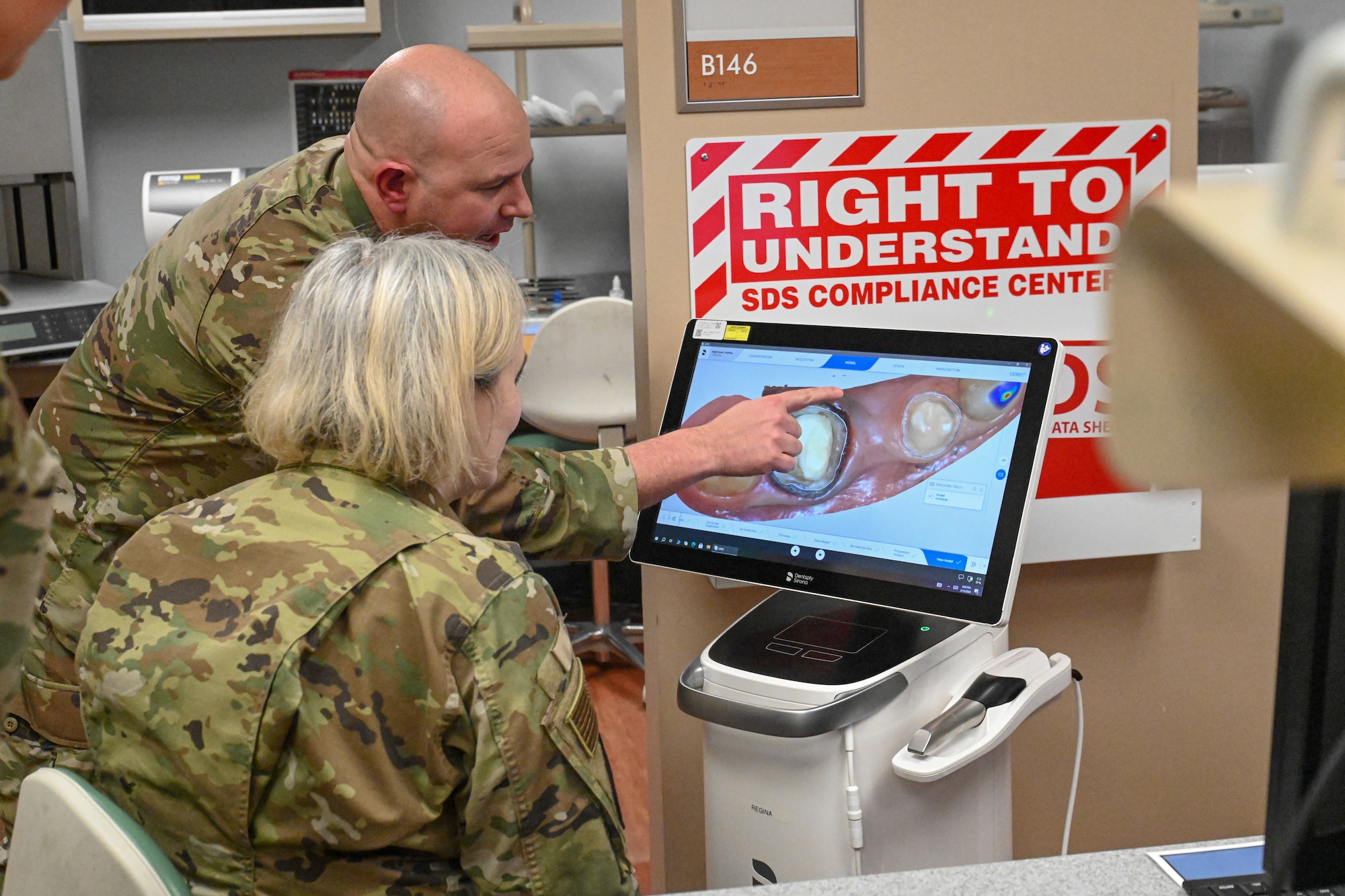 An Airman points out images on a monitor while another Airman listens and watches.