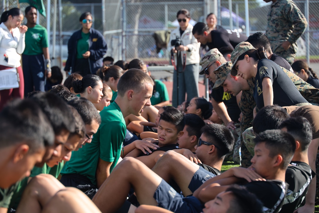 NJROTC students from California execute crunches during an NJROTC field meet at Cabrillo High School in Long Beach, Calif. on Saturday, Dec. 9, 2023. The NJROTC mission is to instill in students in United States secondary educational institutions the values of citizenship, service to the United States, personal responsibility and a sense of accomplishment. (U.S. Marine Corps photo by Cpl. Christian C. Bunch)