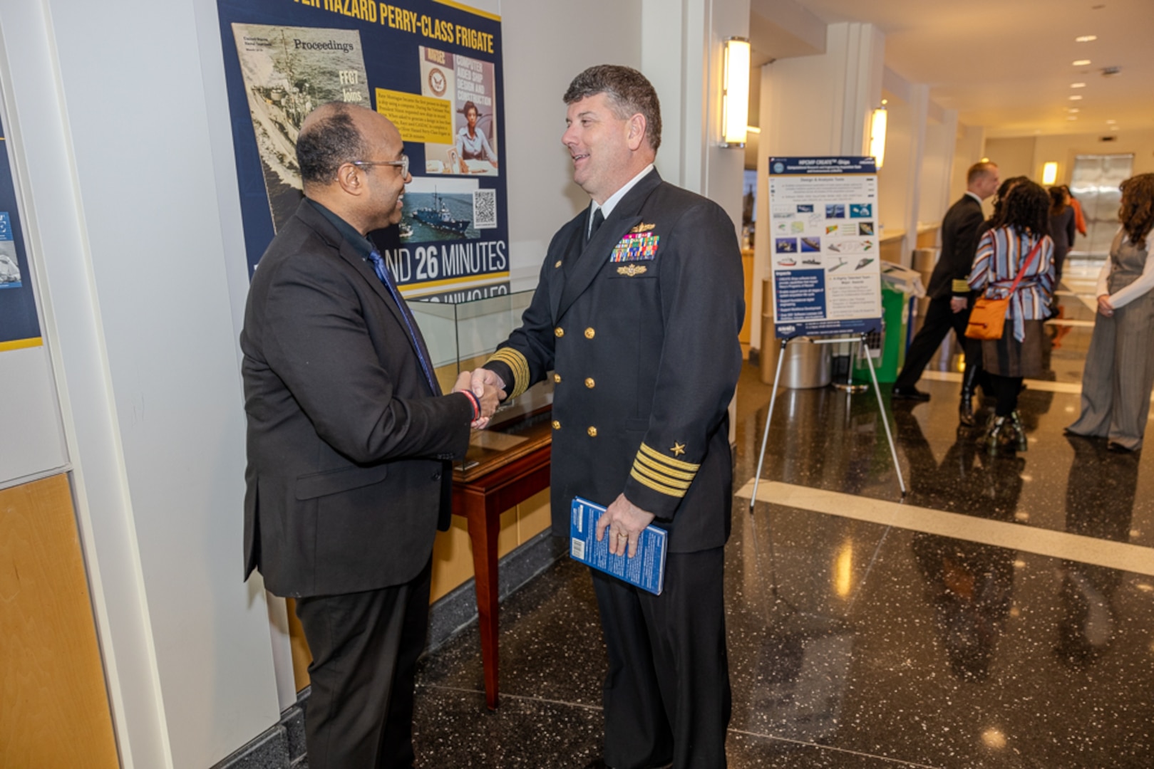 Naval Surface Warfare Center, Carderock Division Commanding Officer Capt. Matthew Tardy (right) speaks to Dr. David Montague, the son of Navy icon Raye Montague.