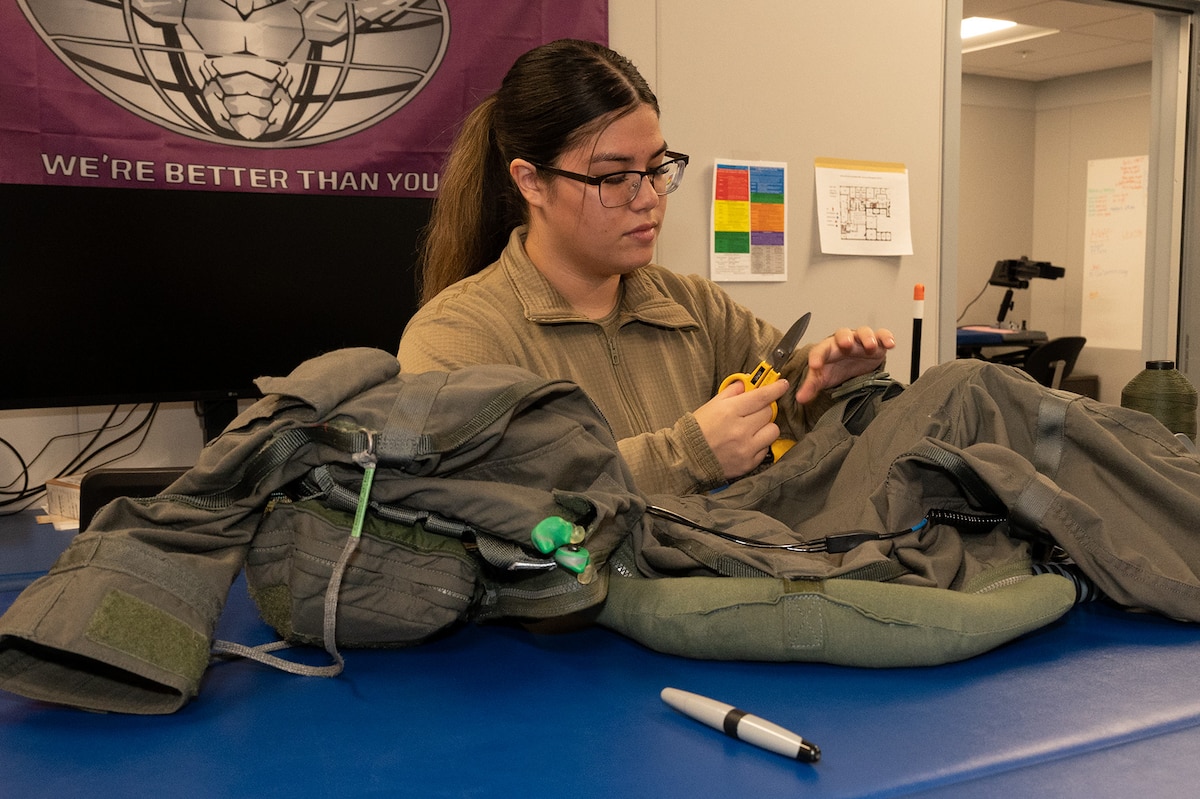 U.S. Air Force Airman 1st Class Tia Heyob, 356th Fighter Squadron aircrew flight equipment journeymen, assists the 355th Fighter Squadron by cutting threads on a pilot's gear before a sortie on Eielson Air Force Base, Alaska, Feb. 14, 2024.