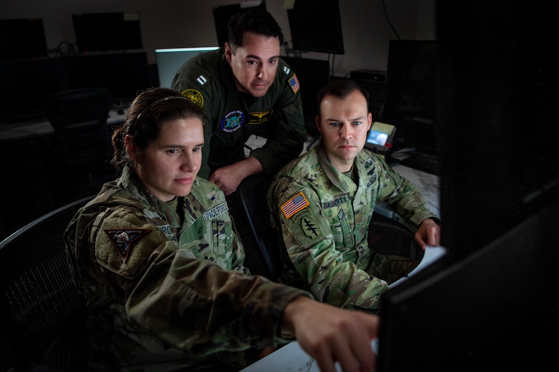 U.S. Space Force Maj. Jerra Brown, National Space Defense Center director of force development, U.S. Navy Lt. Matthew Dring, NSDC space planner, and U.S. Army Maj. Mitchell Daugherty, NSDC special technical operations chief and chief of combat operations, look at a computer screen in support of Keen Edge 24 at Schriever Space Force Base, Colo., Feb. 8, 2024. Members of the NSDC supported KE24 both at home and in Hawaii. KE24 is designed to increase integrated joint operational capability, refine command and control procedures, and improve interoperability among the participating countries to respond to a variety of crises and contingencies in the Indo-Pacific region. (U.S Space Force photo by Tiana Williams)