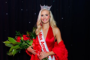 A glamorous woman holding a bouquet of flowers poses for a photo.