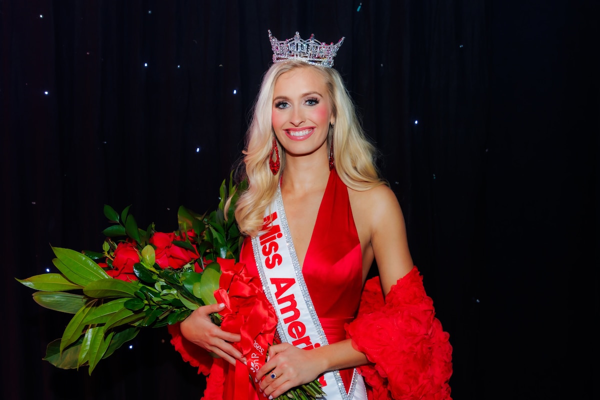 A glamorous woman holding a bouquet of flowers poses for a photo.