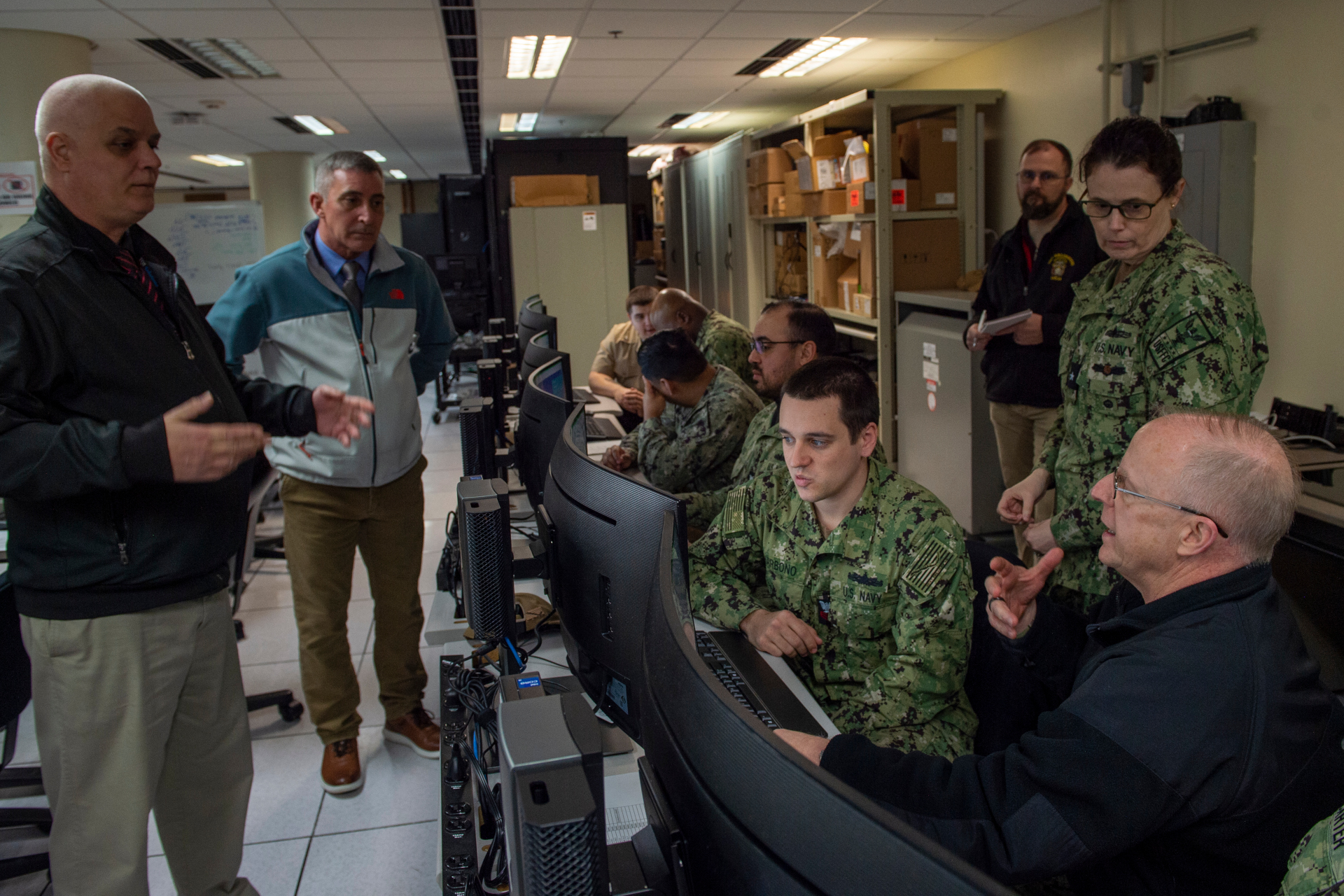 Electronics Technician Second Class Cody Carter demonstrates to Adm. Daryl Caudle, commander, U.S. Fleet Forces Command, (right) aspects of the Naval Maintenance Repair and Overhaul (NMRO) system at the Naval Information Warfare Cetner Atlantic software test laboratory at Naval Station Norfolk, Feb. 13, 2024.