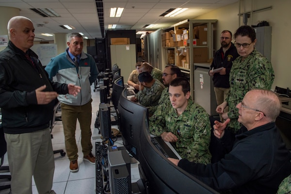 Electronics Technician Second Class Cody Carter demonstrates to Adm. Daryl Caudle, commander, U.S. Fleet Forces Command, (right) aspects of the Naval Maintenance Repair and Overhaul (NMRO) system at the Naval Information Warfare Cetner Atlantic software test laboratory at Naval Station Norfolk, Feb. 13, 2024.