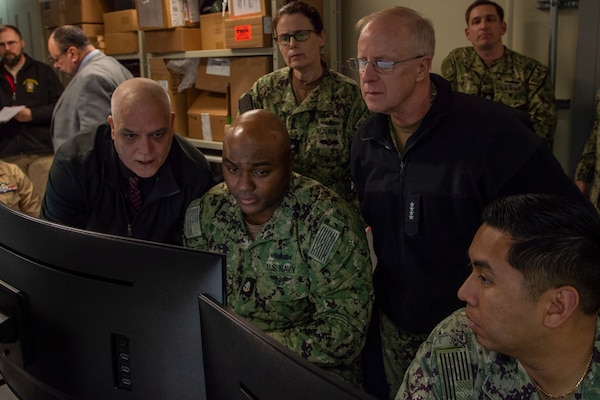 Electronics Technician Second Class Cody Carter demonstrates to Adm. Daryl Caudle, commander, U.S. Fleet Forces Command, (right) aspects of the Naval Maintenance Repair and Overhaul (NMRO) system at the Naval Information Warfare Cetner Atlantic software test laboratory at Naval Station Norfolk, Feb. 13, 2024.