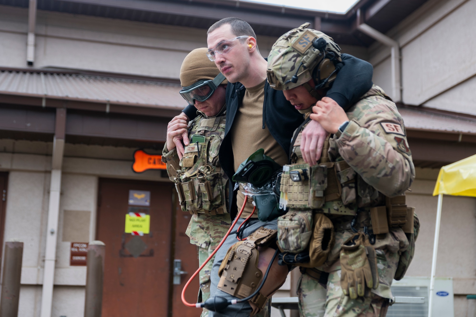 U.S. Air Force Airman 1st Class James Fromm, left, and Senior Airman Melchor Sevillano, right, both 51st Security Forces Squadron defenders, assist Senior Airman Tyler Canniff, simulated triage victim, to an ambulance during a simulated active shooter response training at Osan Air Base, Republic of Korea, Feb. 14, 2024. The scenario enabled integrated training between the 51st SFS and 51st Medical Group, and enhanced Airmen’s lifesaving skills. (U.S. Air Force photo by Senior Airman Trevor Gordnier)