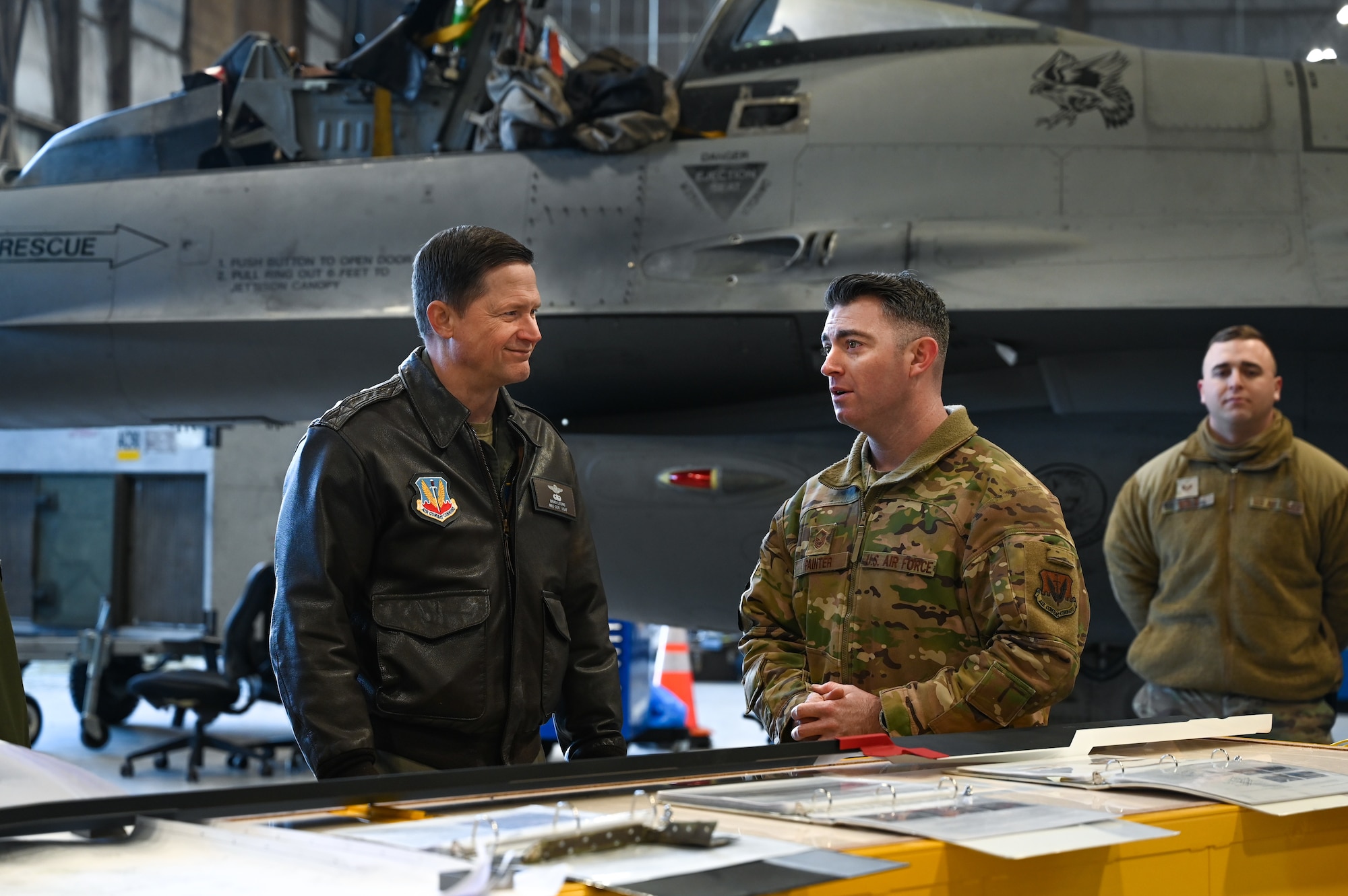 U.S. Air Force Maj. Gen. receives a brief by a military maintenance personnel.