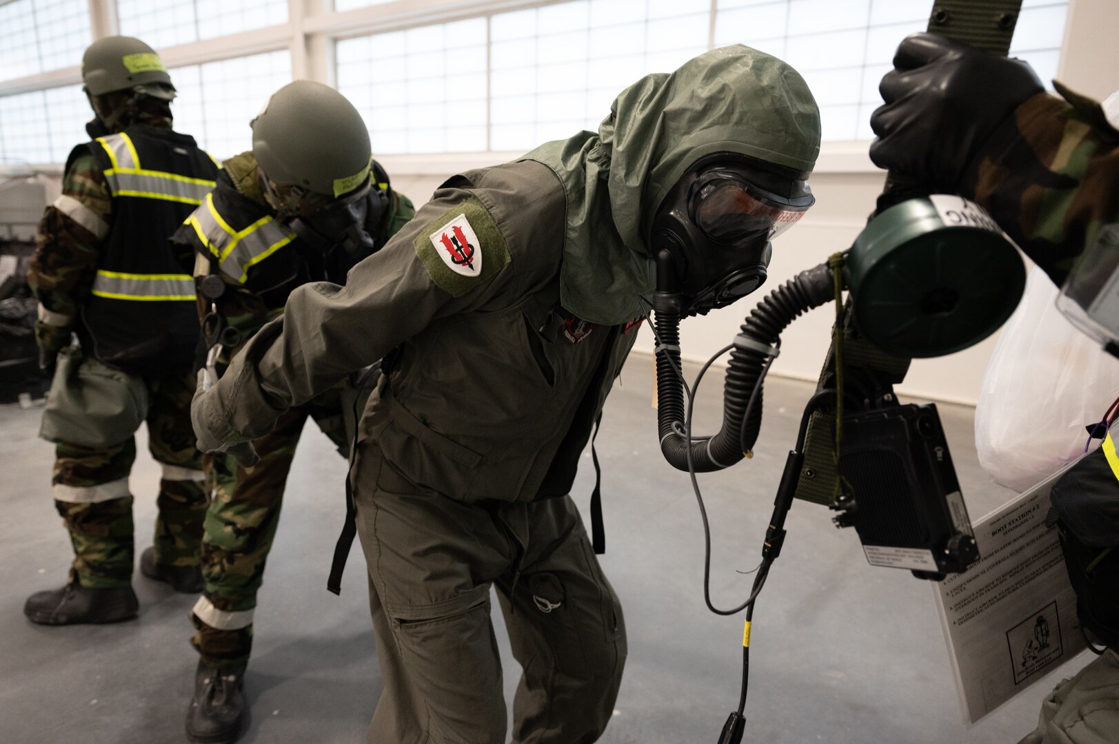 Airmen from the 155th Air Refueling Wing perform a simulated uniform decontamination of their specialized suit as part of the Mission-Oriented Protective Postures gear during a large-scale readiness exercise Feb. 4, 2024, on National Guard airbase in Lincoln, Nebraska.
