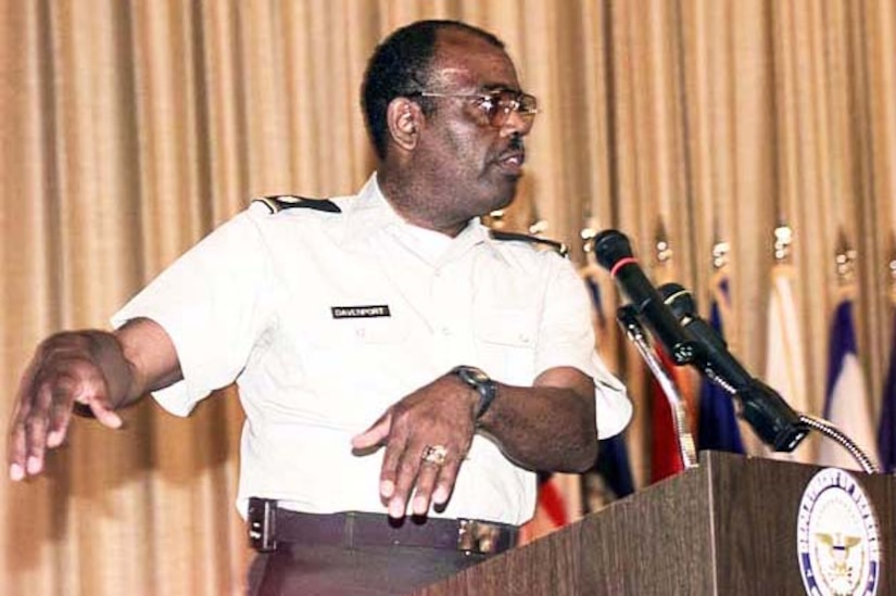 A man speaks into microphones mounted on a podium.