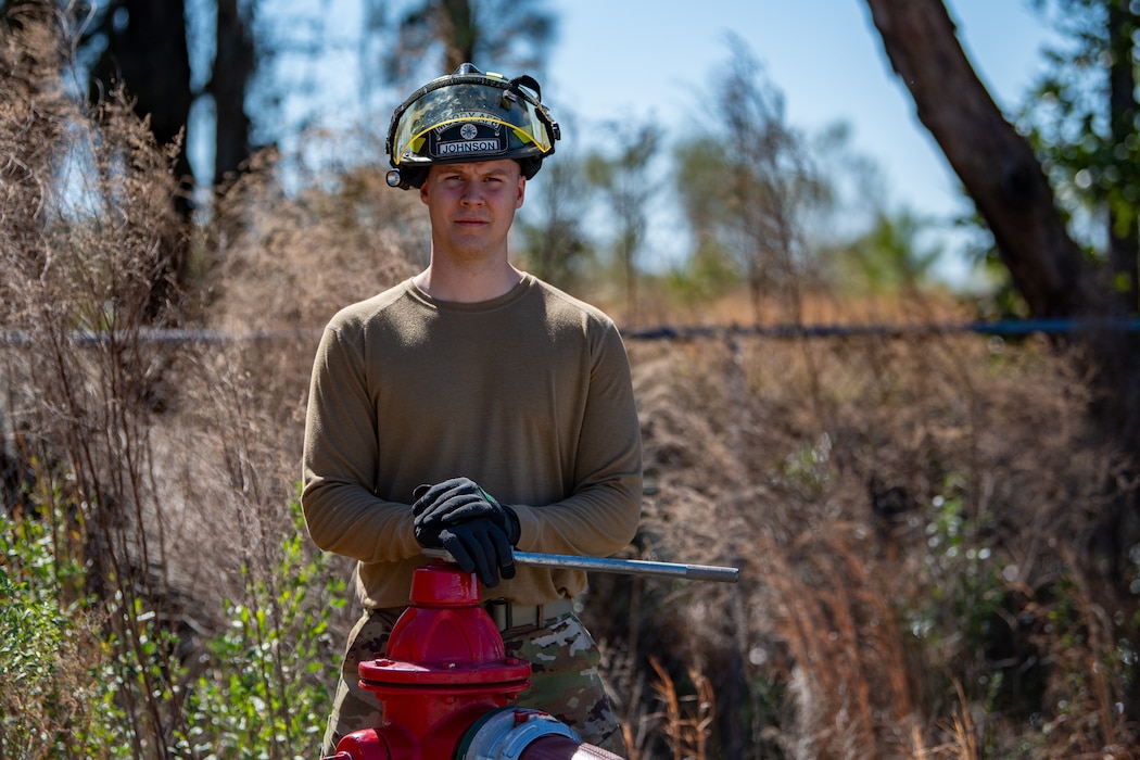 An Airmen stands behind a fire hydrant