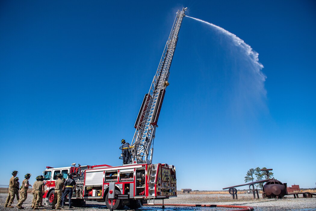 Airmen watch as a water hose sprays water onto an aircraft