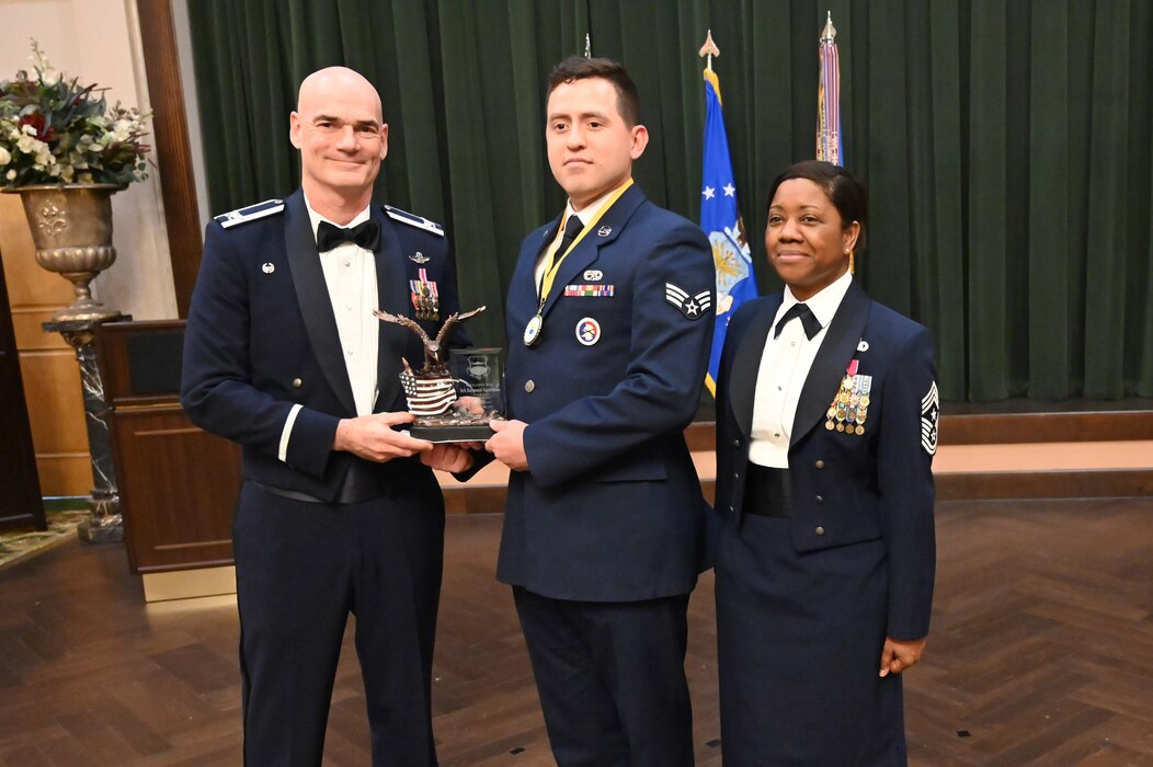 Col. William Gutermuth, 433rd Airlift Wing commander, and Chief Master Sgt. Takesha Williams, 433rd AW command chief, present the Honor Guard/Guardian of the Year award to Senior Airman Raymond Santellana, 433rd Aircraft Maintenance Squadron, at the wing’s annual awards ceremony Feb. 3, 2024, at Joint Base San Antonio-Lackland, Texas. (U.S. Air Force photo by Tech. Sgt. Jacob Lewis)
