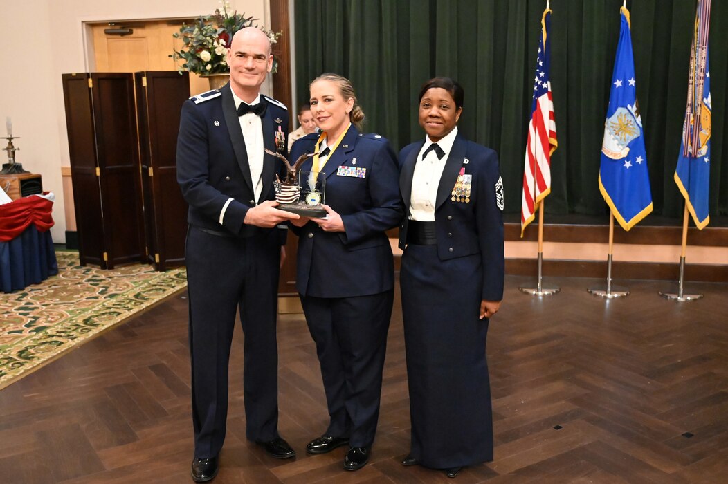 Col. William Gutermuth, 433rd Airlift Wing Commander, and Chief Master Sgt. Takesha Williams, 433rd AW command chief, present the Field Grade Officer of the Year award to Lt. Col. Brandy Ramos, 433rd Aerospace Medicine Squadron, at the wing’s annual awards ceremony Feb. 3, 2024, at Joint Base San Antonio-Lackland, Texas. (U.S. Air Force photo by Tech. Sgt. Jacob Lewis)