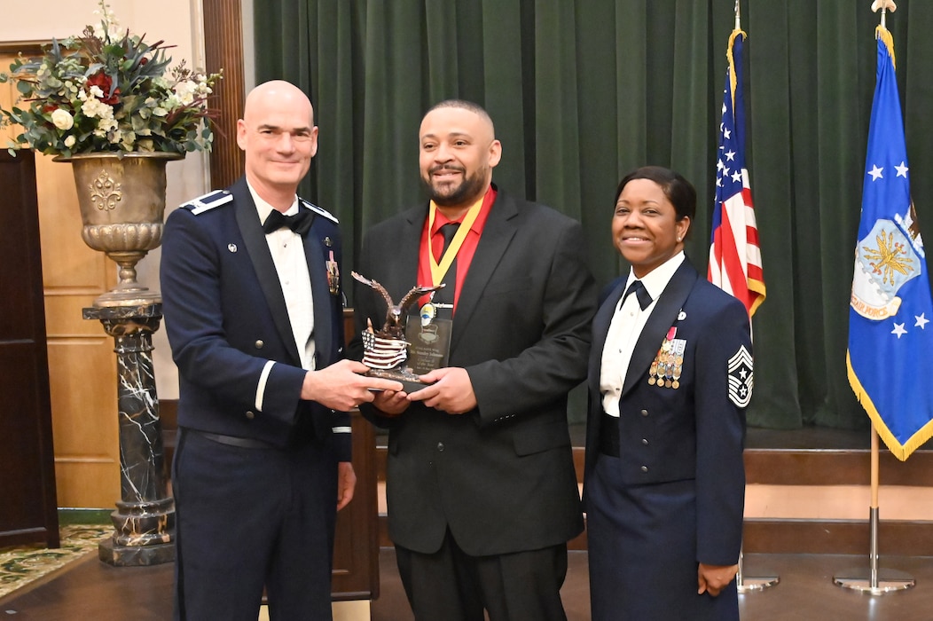 Col. William Gutermuth, 433rd Airlift Wing commander, and Chief Master Sgt. Takesha Williams, 433rd AW command chief, present the Category II Civilian of the Year award to Mr. Stanley Johnson, 433rd Maintenance Group, at the wing’s annual awards ceremony Feb. 3, 2024, at Joint Base San Antonio-Lackland, Texas. (U.S. Air Force photo by Tech. Sgt. Jacob Lewis)