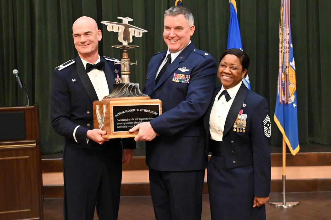 Col. William Gutermuth, 433rd Airlift Wing commander, and Chief Master Sgt. Takesha Williams, 433rd AW command chief, present the Alamo Wing Combat Readiness Spirit award to Lt. Col. Matthew Van De Walle, 433rd Operations Group commander, at the wing’s annual awards ceremony Feb. 3, 2024, at Joint Base San Antonio-Lackland, Texas. (U.S. Air Force photo by Tech. Sgt. Jacob Lewis)