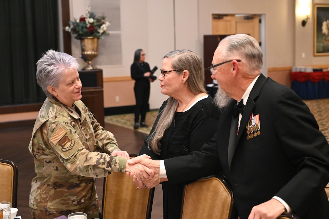 Maureen McAllen, left, 433rd Airlift Wing director of staff and retired Colonel, shakes hands with John Shroyer, right, Retired Command Chief, at the annual award ceremony Feb. 3, 2024, at Joint Base San Antonio-Lackland, Texas. Attendees of the banquet were allowed to wear previous legacy uniforms from past military service years. (U.S. Air Force photo by Tech. Sgt. Jacob Lewis)