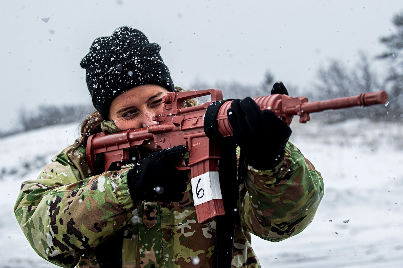 A cadet points a weapon while standing in the snow.