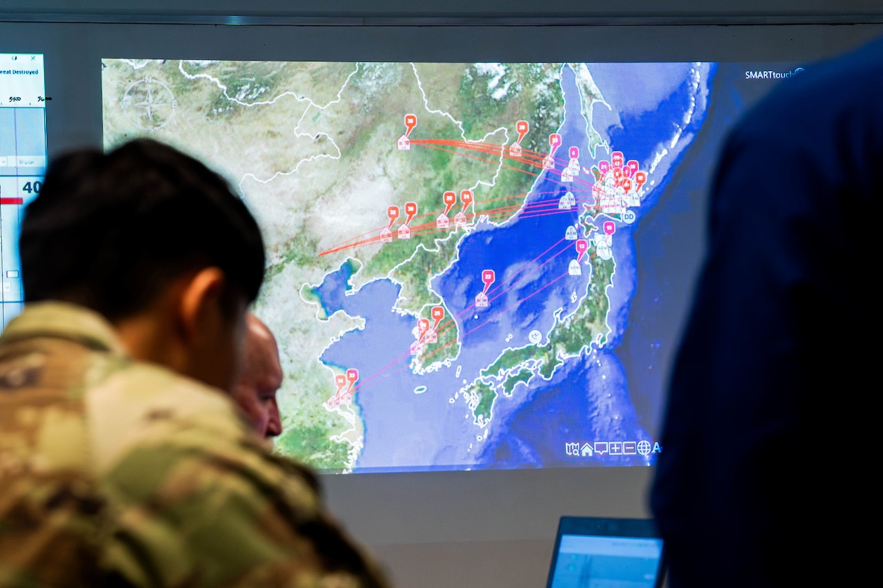 A cadet looks at a monitor with a large map.