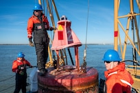 A photo of three men working on a buoy.