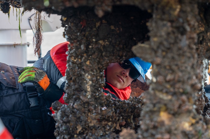 A photo of a man inspecting a buoy.