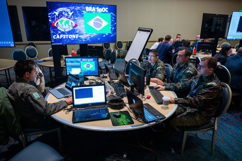 Troops sit around a table looking at laptops.