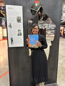 Ohio Education Association Assistant Executive Director  Airica Clay standing in the women in the Air Force exhibit holding the book, Nobody Owns the Sky.