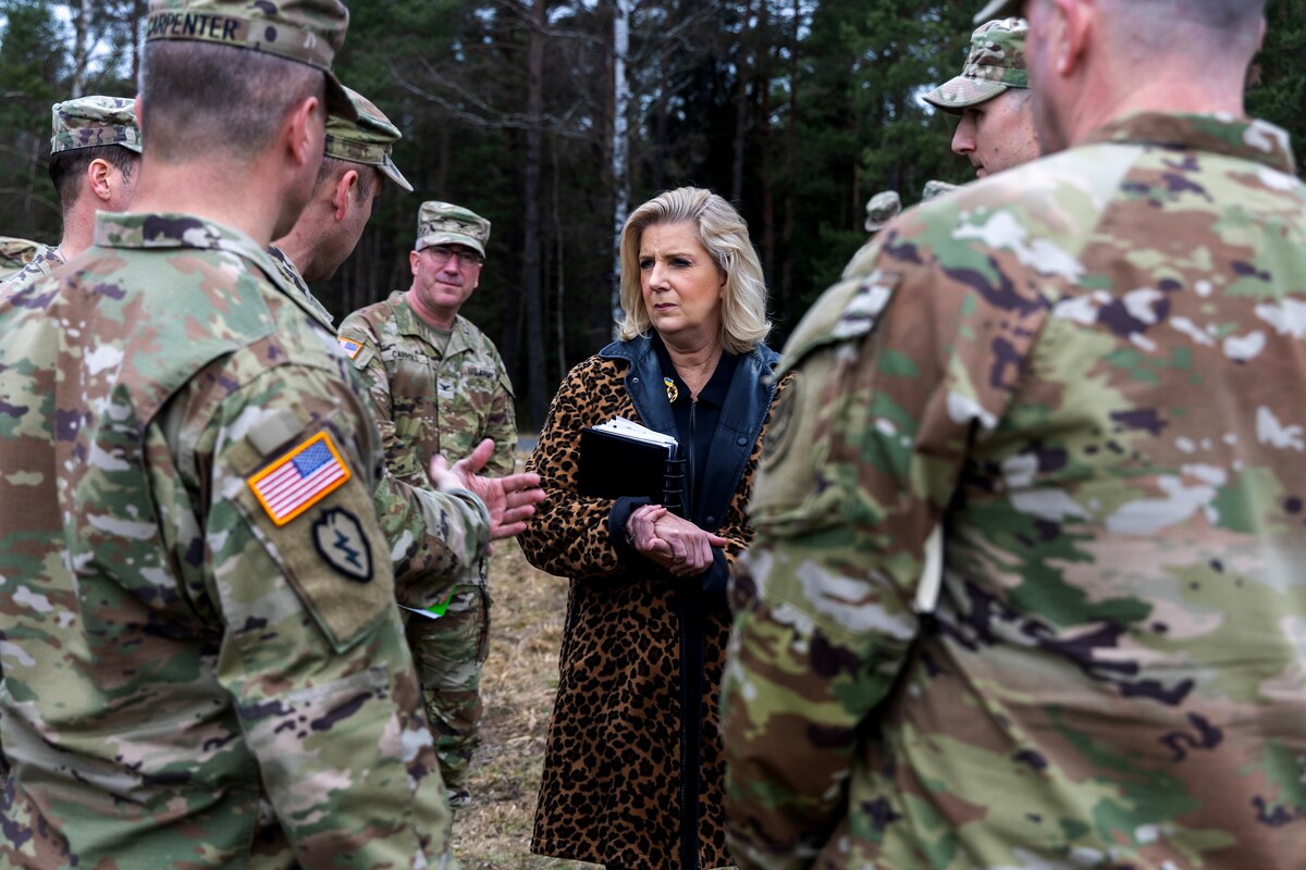 A civilian speaks to service members.