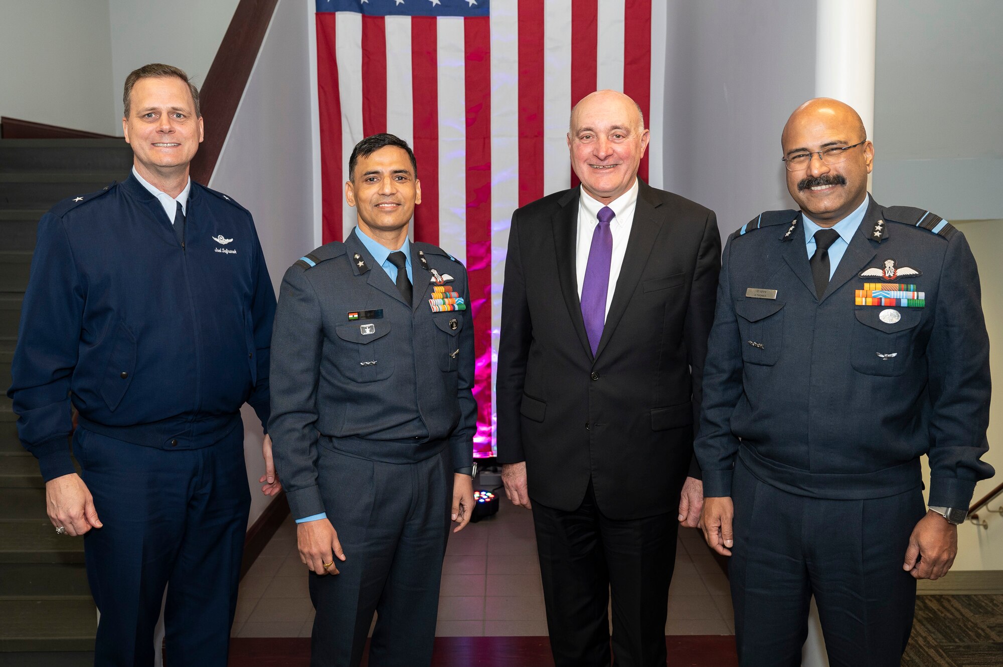 Group of four men standing in front of American flag.