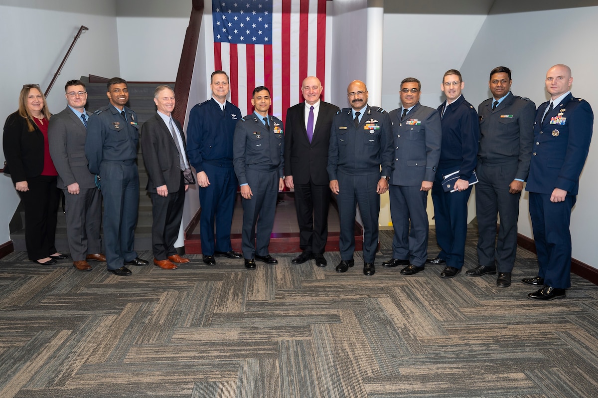 Group of individuals standing together in front of American flag.