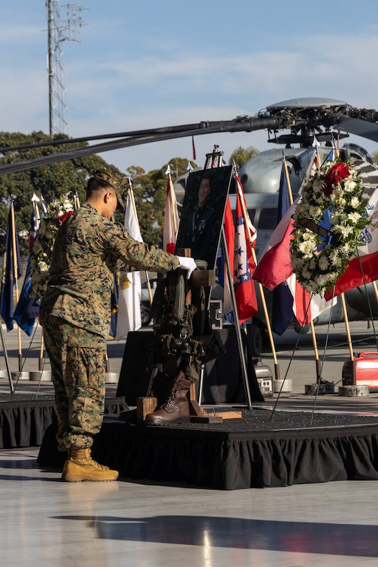 A U.S. Marine with Marine Heavy Helicopter Squadron (HMH) 361, Marine Aircraft Group 16, 3rd Marine Aircraft Wing, places a flight vest on a battlefield cross in honor of Capt. Miguel Nava during a memorial ceremony honoring the five Marines of HMH-361 at Marine Corps Air Station Miramar, California, Feb. 16, 2024.  More than 550 Marines, family and friends gathered to pay tribute to the five Marines who lost their lives as the result of a CH-53E mishap on Feb. 6, 2024, in Pine Valley, California. (U.S. Marine Corps photo by Staff Sgt. Antonio De La Fuente)