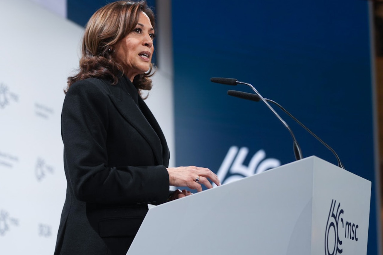 A person in a business suit stands at a lectern.